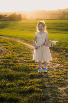 Little girl smiling and holding a windmill, sunset