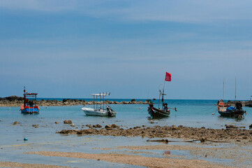 Fishing boats anchored in clear blue sea near rocky shore