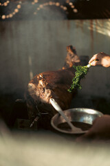 Close-up of seasoning whole roasted meat on spit