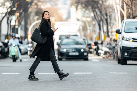 Entrepreneur woman talking on the phone while crossing a city street during the day