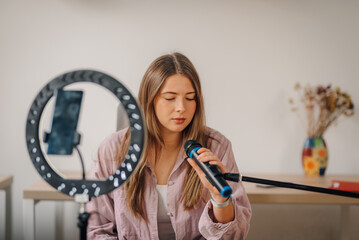 Young woman recording podcast or song using microphone and smartphone