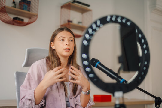 Young woman recording a video blog using a ring light and microphone