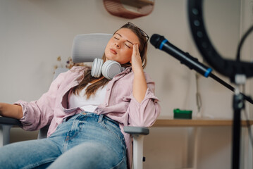 Tired female podcaster relaxing after recording podcast from home
