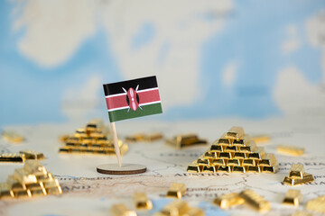 Kenyan flag stands proudly amidst miniature gold bars on a world map, illustrating national...