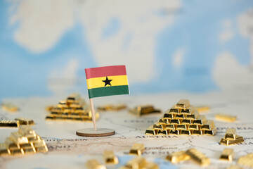 Ghanaian flag standing amidst glittering gold bars on a world map, reflecting the nation's rich...