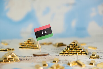 Libyan flag stands prominently amidst glittering gold bars on a world map, symbolizing national...