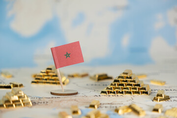 Moroccan flag stands among gold bars on a world map, symbolizing national economic power, wealth,...