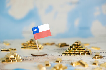A small flag of Chile stands proudly amidst piles of shining gold bars on a world map, symbolizing the nation's rich natural resources and global economic significance