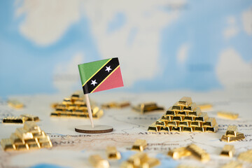Saint Kitts and Nevis flag stands proudly amidst gold bars on a map, depicting national economic...