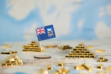 Naklejka premium Falkland Islands flag stands prominently on a global map, surrounded by glistening gold bars, signifying national wealth, strategic resources, and economic investment potential
