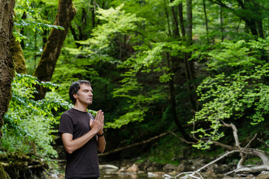 Man meditating in a serene green forest promoting holistic health and mental well-being