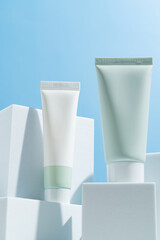 Beauty product mockup. Wellness packaging. Branding spa. Cosmetic cream tubes on blue background. Cream bottle, lotion, mousse, cleanser, shampoo for skincare routine. Copy space