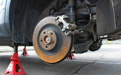  The rear suspension structure with spring and shock absorber is visible in the wheel well of the car with the wheel removed. Dismantled wheel provides access to repair of the shock absorbers