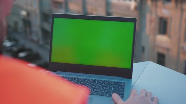 Man engineer using laptop computer with green screen on balcony worker project occupation builder technology mock-up professional male safety device computer slow motion