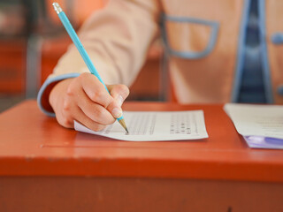 Closeup of hands female of students taking exams in a classroom, exams in school, writing and reading book. Homework and examinations in Asian. Education knowledge and learning. Concept brainstorming