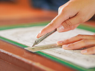 Closeup hand female using cutter to cut the paper in classroom at kid school. Lifestyle Concept...