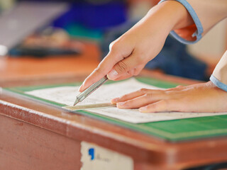 Closeup hand female using cutter to cut the paper in classroom at kid school. Lifestyle Concept...