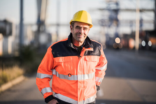 Smiling worker wearing reflective jacket at commercial dock