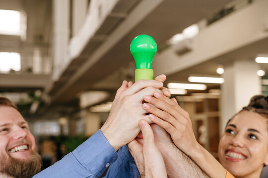 Hands holding green light bulp symolizing green energy - Powered by Adobe