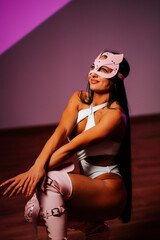 Dancer in pink cat mask performs in studio with striking poses and vibrant lighting
