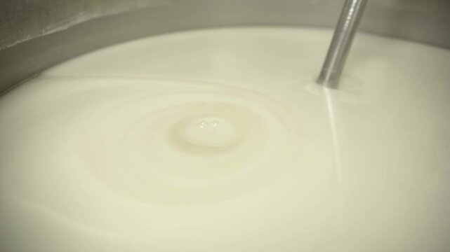 Close-up view of white liquid mixing during pharmaceutical formulation.