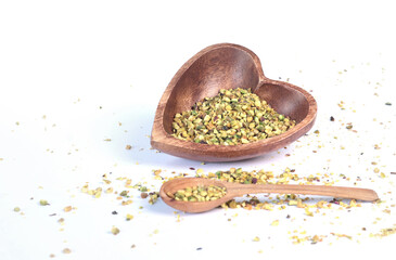 Crushed pistachio nuts in wooden bowl and heart-shaped spoon for cooking. Environmentally friendly product and health.