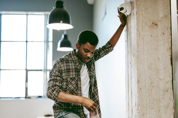 Young man inspecting a security camera in a modern workspace during the day