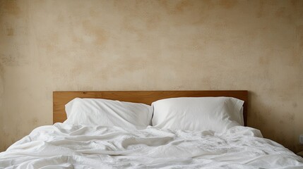 Simple bed with white sheets and textured beige wall.
