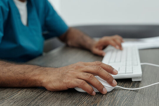 Hands of Unrecognizable Male Doctor Using Desktop Computer at Work in Hospital Office