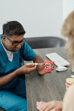 Mature Dentist Demonstrating How to Clean Teeth with Braces using Dental Model