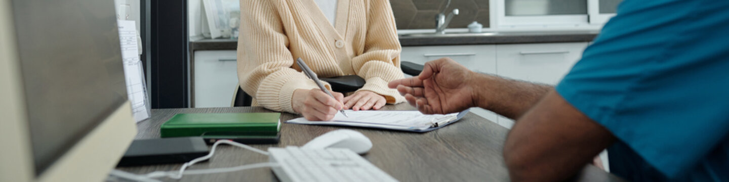 Female Patient Signing Medical Agreement during Appointment in Modern Clinic