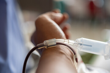 Close-up of a blood donation tube connected to a donor's arm, showing blood flow through a...
