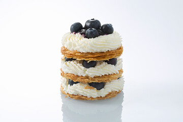 Gourmet Blueberry Mille-Feuille Stack with Piped Cream on White Reflective Surface
