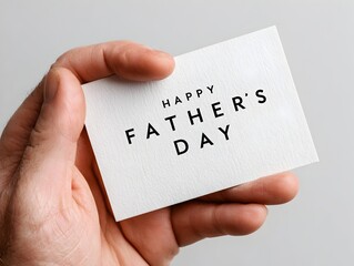 A hand holds a simple white card with elegant black lette reading Happy Father's Day against a neutral background perfect for Father's Day