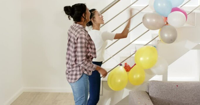Diverse family at home decorating stair railing popping balloon releasing confetti and hugging