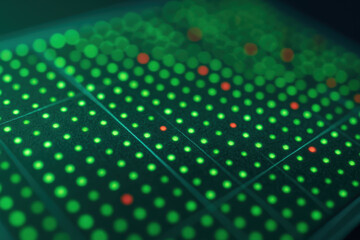 Bioengineering innovation is reflected in this close up of digital interface with green and red illuminated dots creating futuristic pattern
