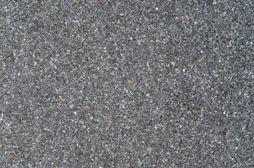 Granular dark grey abrasive texture forms detailed close up surface background. Uniform rough pattern material appears across full frame ideal for graphic design