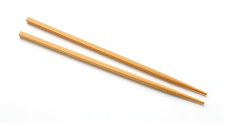 A pair of light brown wooden chopsticks lying diagonally on a white background