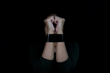 Tech Trauma Woman bound by smart watch with face hidden in shadow.