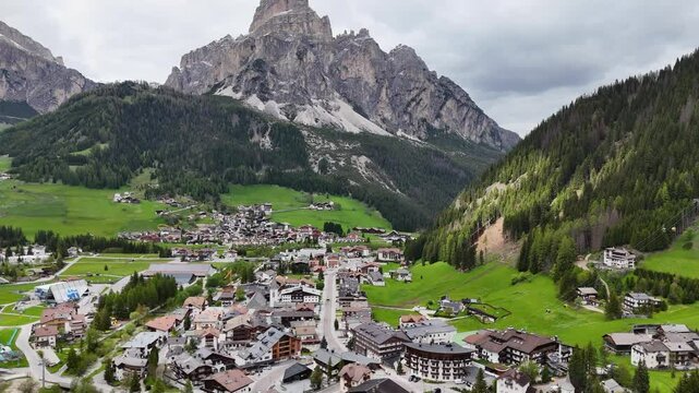 Corvara village nestled in the Dolomites with a towering rocky peak and green valley