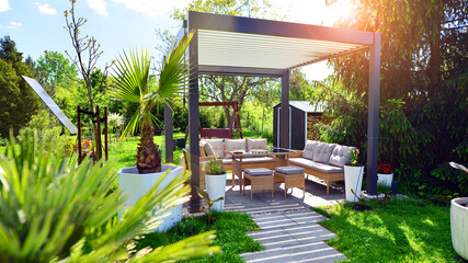 Modern aluminum pergola with stylish garden furniture in a beautiful garden.
