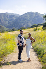 A joyful couple, deeply in love, enjoys the beautiful outdoors, fully embracing the warmth of...