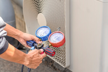 Air repair mechanic using measuring equipment for filling industrial factory air conditioners.	