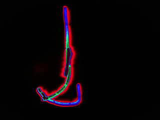 Glowing English letter J. On a black background with colored neon lines, a letter of the English alphabet is written by hand. The letter glows pink-red, creating a green-blue halo around it.