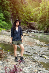 Naklejka premium Young Asian Woman Exploring Nature by a River in Hiking Gear During Outdoor Adventure