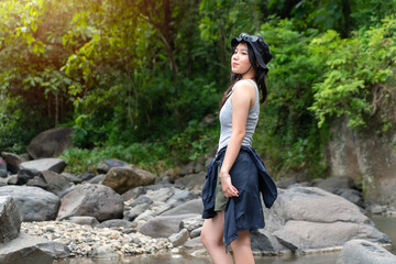 Confident Asian Woman Smiling in Lush Green Forest During Outdoor Adventure and Nature Exploration
