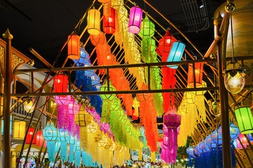 Vibrant hanging paper lanterns illuminating the festive space, bright colorful lampshades on background night sky, cultural celebrations and gatherings.
