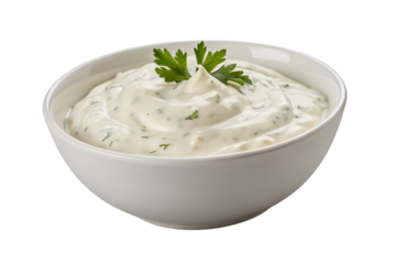 A bowl of creamy white sauce with green herbs and a parsley garnish on a black background isolated