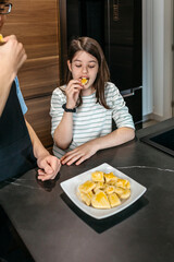 Sister and brother tasting homemade cookies in modern kitchen