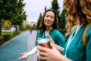 Two healthcare professionals engage in a friendly conversation while enjoying a walk in a park on a...